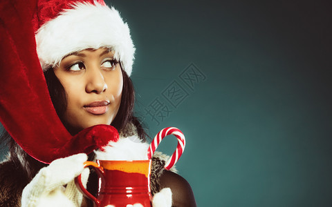 圣诞时间概念穿着圣诞帮手帽子拿着红杯的喝着热饮料图片