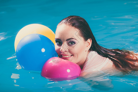 在游泳池水中快乐的女子与气球玩乐穿着湿白衬衫的少女在放松水中快乐