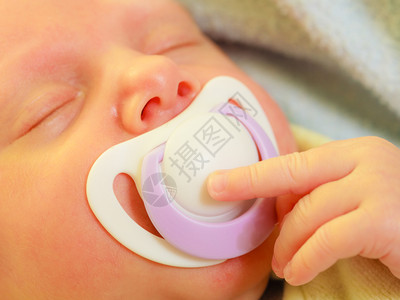婴儿护理童年概念的美丽婴儿出生后在床上平静睡着嘴里有茶婴儿出生后用茶睡在嘴里婴儿出生后童年概念的美丽婴儿出生后平静地睡在床上嘴里图片