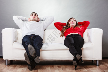 躺够快乐笑的年轻夫妇在家沙发上放松冷静无忧虑的男女头背着双臂躺