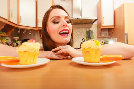 女人看着美味的蛋糕上面有甜的奶油和水果喜欢贪食的概念女人看着美味的甜饼图片