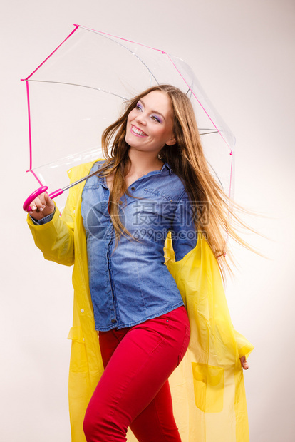 身着防水黄色大衣站在雨伞下玩得开心的雨中微笑女孩气象预报和天季节概念身着雨伞下防水大衣的妇女图片