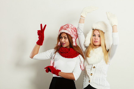 时装冬季饰概念两个金发女孩和黑穿着温暖的红白衣服玩得开心两个女孩穿着毛帽围巾手套有吸引力两个女孩穿着温暖的冬装玩得开心图片