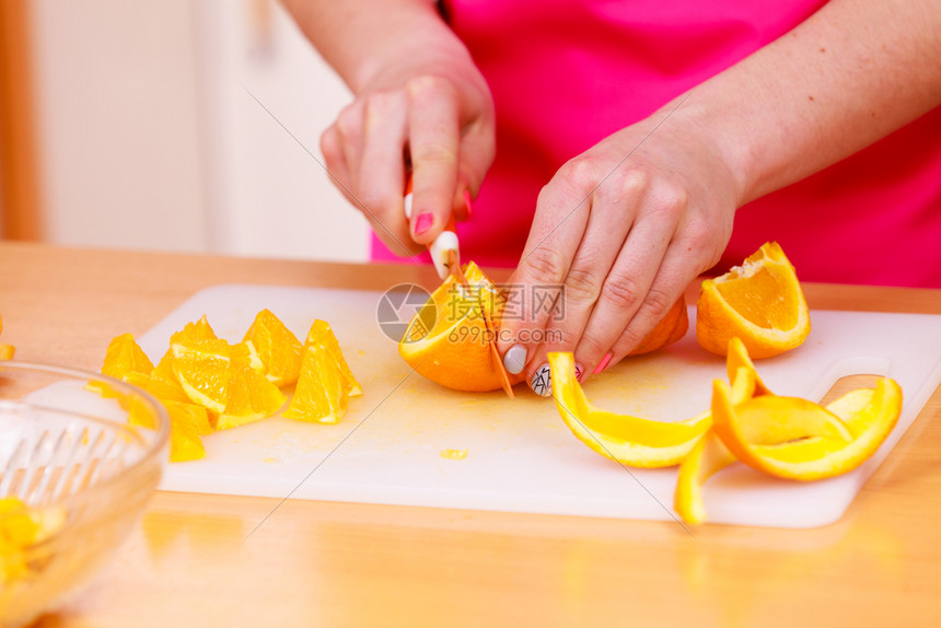 家庭主妇在切菜板上切开橙子图片