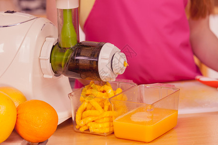 厨房的年轻女家庭主妇在果汁机中制造新鲜橙汁准备营养的维他命包装饮料健康食素和人的概念图片