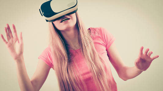 年轻女身着虚拟现实戴的护目镜头盔软箱伸展臂连接技术新一代和进步概念工作室拍摄灰色女孩身着虚拟现实戴的护目镜图片