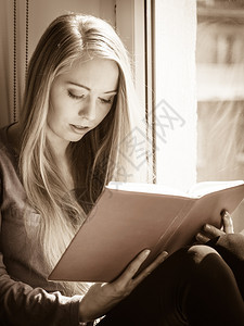 休闲文学和人的概念少女在家阅读书时坐窗边平静和舒适妇女坐在窗边看书家阅读女孩坐在窗边图片