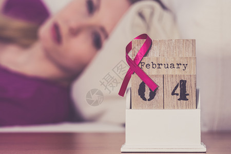 躺在床上的妇女看着日历今天是4个世界乳癌日与粉红色认识丝带约会保健和医学概念睡觉的妇女日历上世界乳腺癌日图片