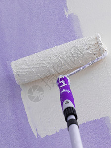使用滚刷在墙上涂油漆的人家庭翻新概念墙上涂油漆的人图片