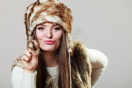 冬天女时装工作室灰色背景的穿毛帽年轻美女肖像图片