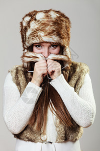 冬天女时装工作室灰色背景的穿毛帽年轻美女肖像图片