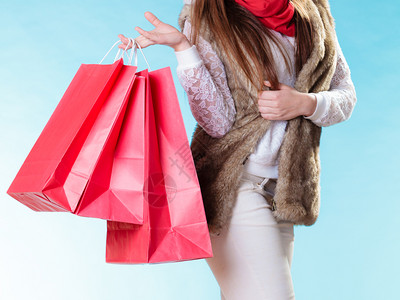 红色衣服女孩穿着温暖衣服的冬季妇女穿着蓝色的红纸购物袋女孩买销售和零背景