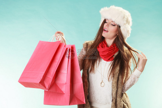 穿着毛帽的年轻女孩穿着工作室蓝色冬季时装服销售买包的女人冬季时装图片