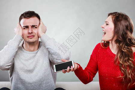 愤怒的老婆对丈夫大喊叫在手机上显示情人妇的短信愤怒女朋友发现男的恋情背叛欺骗男人的耳朵妻子对丈夫大喊叫欺骗男人背叛图片