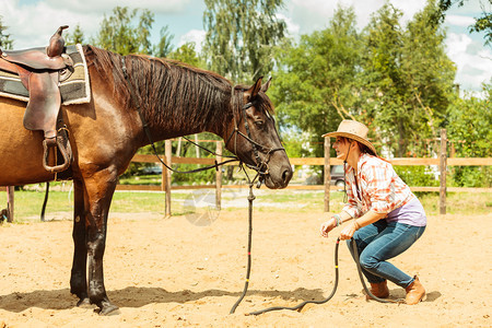 怀着马帽的西部活跃女牛仔在农村牧场的美国女孩骑着马的西部女牛仔图片