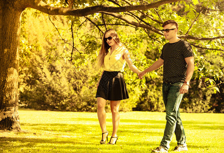 情侣在公园拉手年轻女孩和男一起散步夫妇在公园拉手背景图片