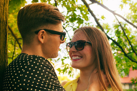 快乐的年轻情侣穿着太阳镜在夏日公园露天约会图片