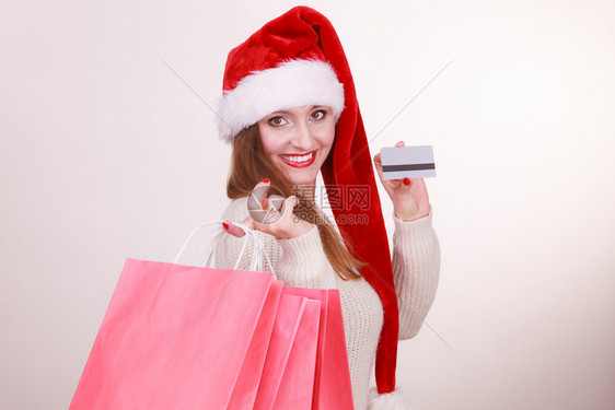 圣诞购物的快乐女孩穿着圣塔帽袋的年轻快乐女人节日庆祝商业快乐休闲概念图片