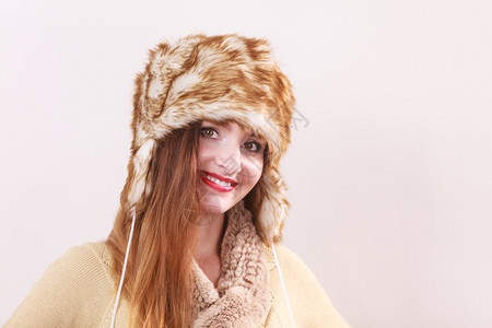 穿着时服装的年轻笑着女人穿时装的冬衣毛帽工作室拍摄在灰色上图片