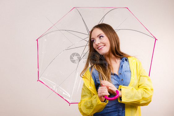 身着防水黄色大衣站在雨伞下玩得开心的雨中微笑女孩气象预报和天季节概念身着雨伞下防水大衣的妇女图片