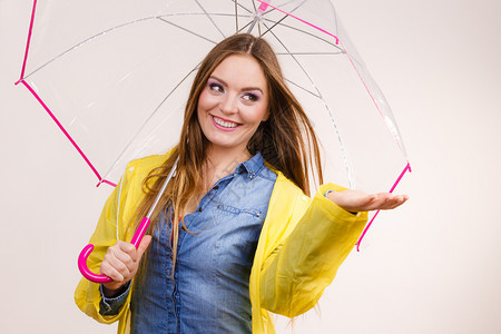 身着防水黄色大衣的女雨站在透明伞下伸展的手臂上出来捕捉雨水滴落的预测天气季节概念穿防雨大衣的女带伞预测图片