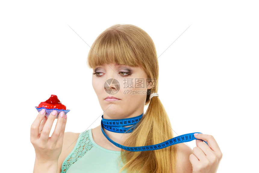 女人的脖子被蓝色测量胶带围住手拿着蛋糕试图抵制诱惑体重损失的饮食进困境贪婪的概念女人拿着蛋糕试图抵制诱惑图片