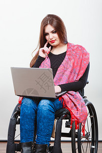 残疾女在网上冲浪使用膝型电脑坐在轮椅上的年轻女互联网技术教育残疾概念女在网上冲浪图片