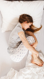 疲惫的睡眠概念疲惫的睡眠女孩处于胎儿状态的年轻女士在床上休息疲惫的睡眠女孩在床上休息图片