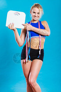健康生活方式身妇女配有许多计量磁带的体健美妇女拥有重量级磁带工作室拍摄的是蓝色背景配有重量级测磁带的妇女配有重量级测磁带的妇女图片