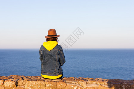 穿着旅行服和帽子坐着看蓝色的海洋和天空旅行概念照片穿旅行服和帽子坐着看蓝色的海洋和天空图片