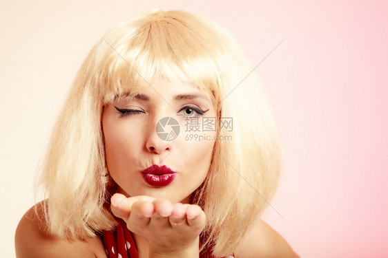 旧式针刺风格时髦女人的肖像吹吻和眨眼粉红色穿金假发和红裙子的女孩图片