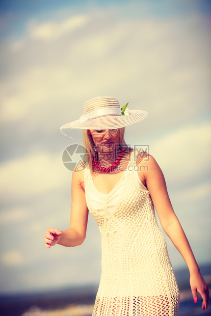 穿着白裙子和戴太阳帽的美丽金发女子肖像图片