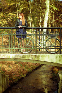 大自然户外概念年轻女士骑着自行车站在边阳光下有条河在闪耀图片