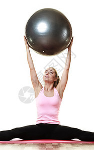 年轻快乐的女青在运动锻炼时用与白隔绝的合身球进行健锻炼图片