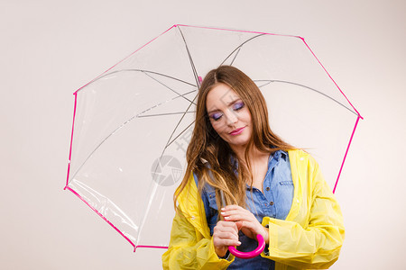 身着防水的黄大衣有透明伞式保护的女时装雨衣少气象学预报和天气季节概念身着防水大衣的妇女则身着雨伞式保护图片