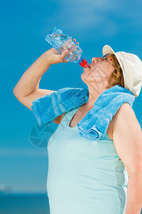 快乐的老年妇女在户外用塑料瓶喝矿泉水图片