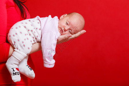 幼童无罪概念小可爱的新生婴儿躺在母亲的手上红色背景小新生婴儿躺在母亲的手上图片