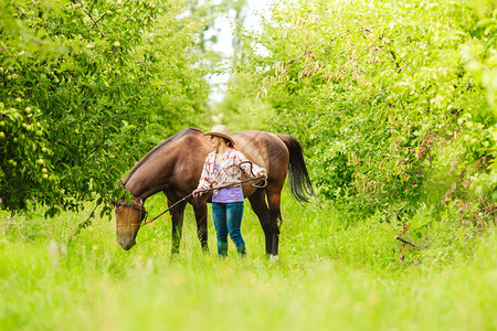 与马一起戴帽子的西部活跃女牛仔在农村牧场的美国女孩有马的西部女牛仔图片