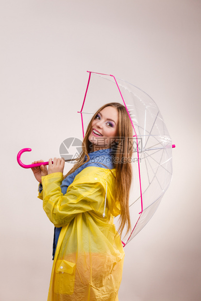 身着防水黄色大衣站在雨伞下玩得开心的雨中微笑女孩气象预报和天季节概念身着雨伞下防水大衣的妇女图片