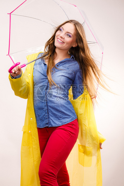 身着防水黄色大衣站在雨伞下玩得开心的雨中微笑女孩气象预报和天季节概念身着雨伞下防水大衣的妇女图片