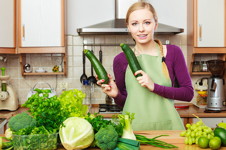 厨房里有许多绿叶蔬菜新鲜有机农产品的妇女在柜台上年轻幸福的家庭主妇手握着马罗苏奇尼健康饮食烹饪素品饮和人的概念在厨房里有绿色蔬菜图片