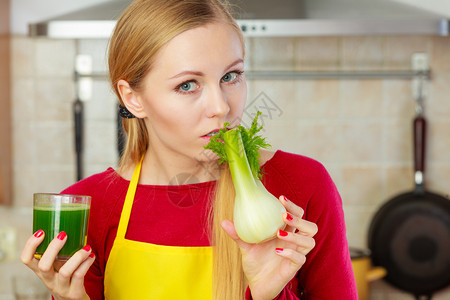 厨房的年轻女子拿着绿色健康蔬菜芬内香水杯厨房的女士拿着蔬菜芬内香水果汁图片