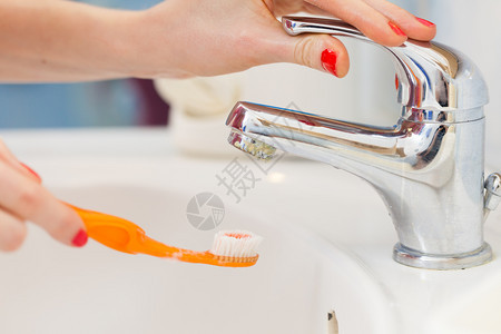 牙科口腔卫生浴室用具概念妇女将牙刷放在水下清洗牙刷妇女图片