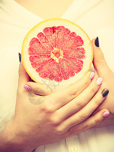 健康饮食减肥脱毒概念妇女手中握着一半的葡萄果柑橘水图片
