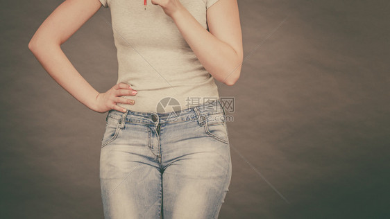 穿紧身牛仔裤和白衬衫展示其身材曲线的女子图片