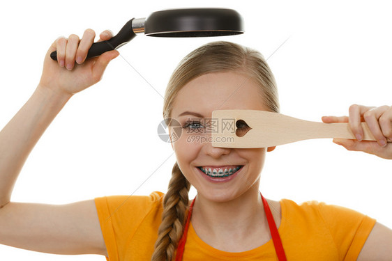 穿着围裙的快乐年轻女子手持小锅和木制烟幕准备在厨房做饭图片