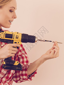 持有黄色钻井机的妇女即将钻探一些东西硬件建筑工地物体概念妇女钻入墙壁图片