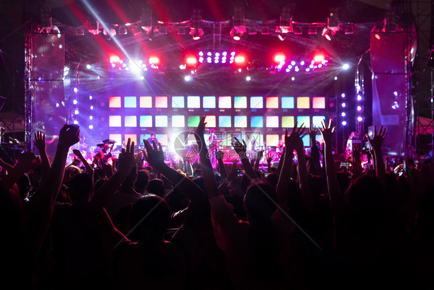 在现场音乐会中欢呼在多彩的舞台灯光面前图片