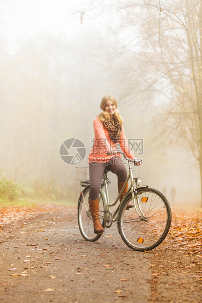 年轻女孩在起雾的公园内骑自行车图片