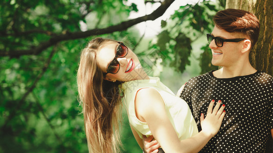 快乐的情侣穿着太阳眼镜的年轻情侣在夏日公园露天约会快乐的情侣在公园图片